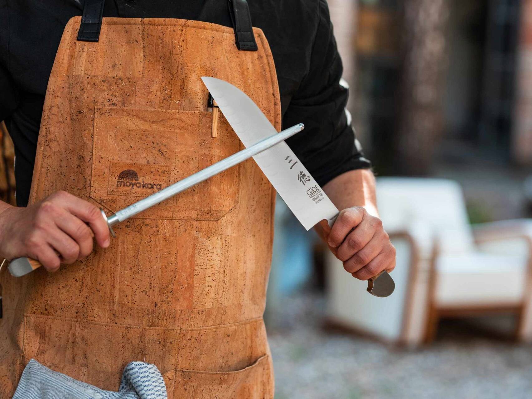 Koch hält Santoku Messer von Güde Solingen und schärft die Klinge mit einem Wetzstahl