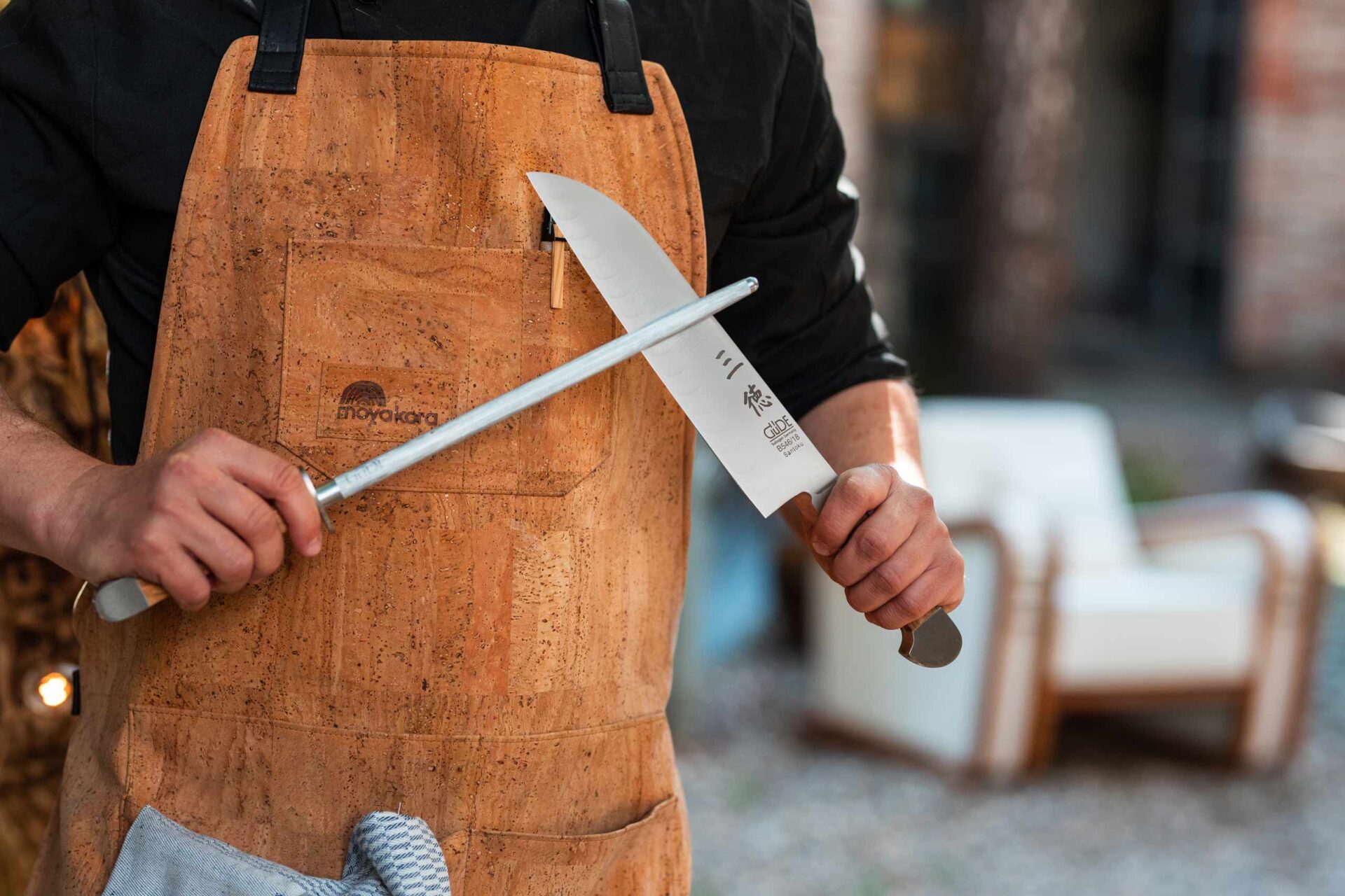 Koch hält Santoku Messer von Güde Solingen und schärft die Klinge mit einem Wetzstahl